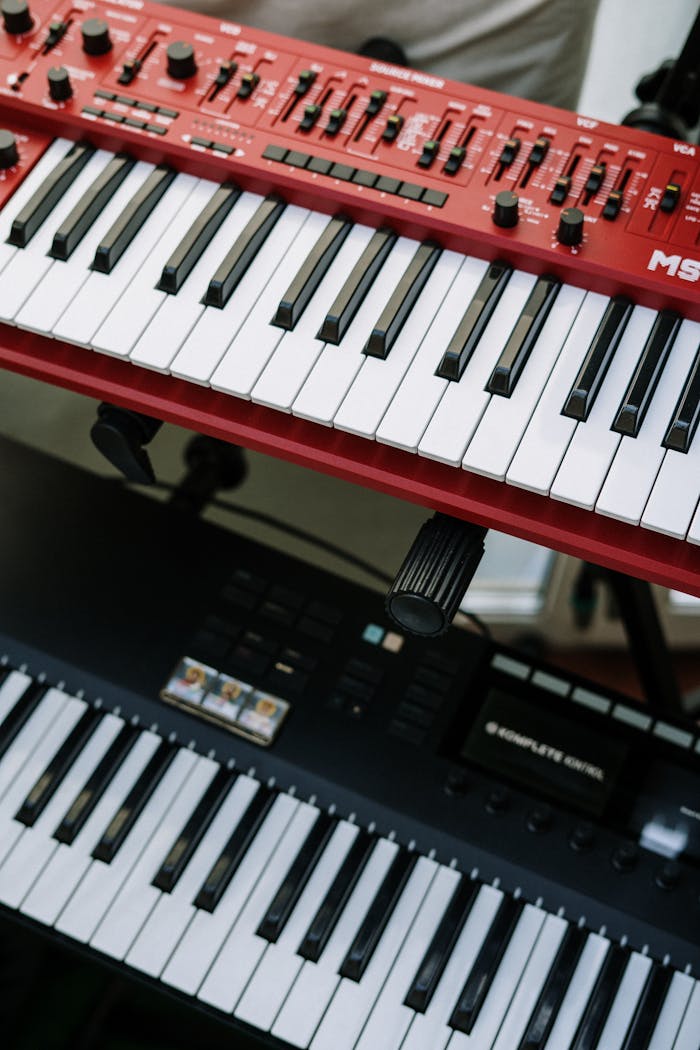services-03 Vertical shot of red and black electronic keyboards in a home studio setting.